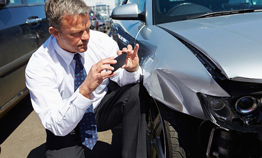 Verkehrs-Rechtsschutz - Mann kniet vor beschädigtem Auto